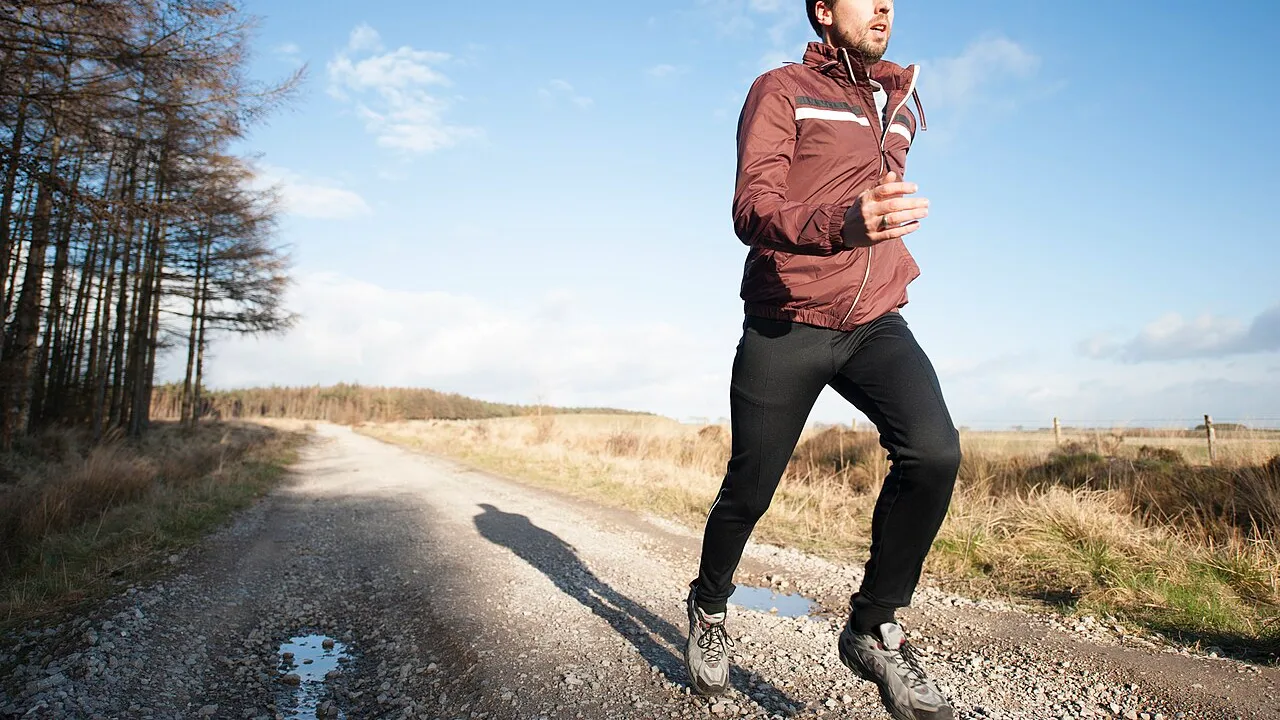 Persona che corre su un sentiero ai margini del bosco